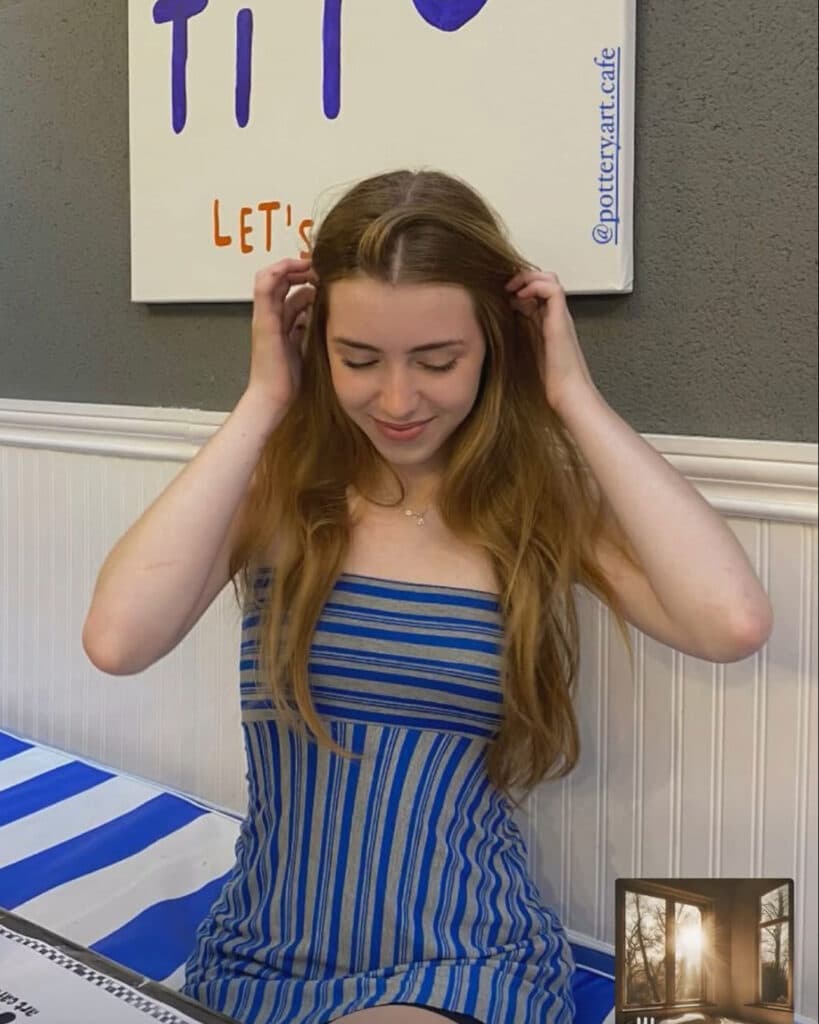 Joven sonriendo en el local, cartel decorativo y mantel a rayas, ambiente de taller de cerámica — imagen 3 de 4